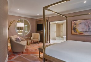Une chambre d’hôtel moderne avec un grand lit, un miroir rond, une chaise, une petite table et un téléviseur.