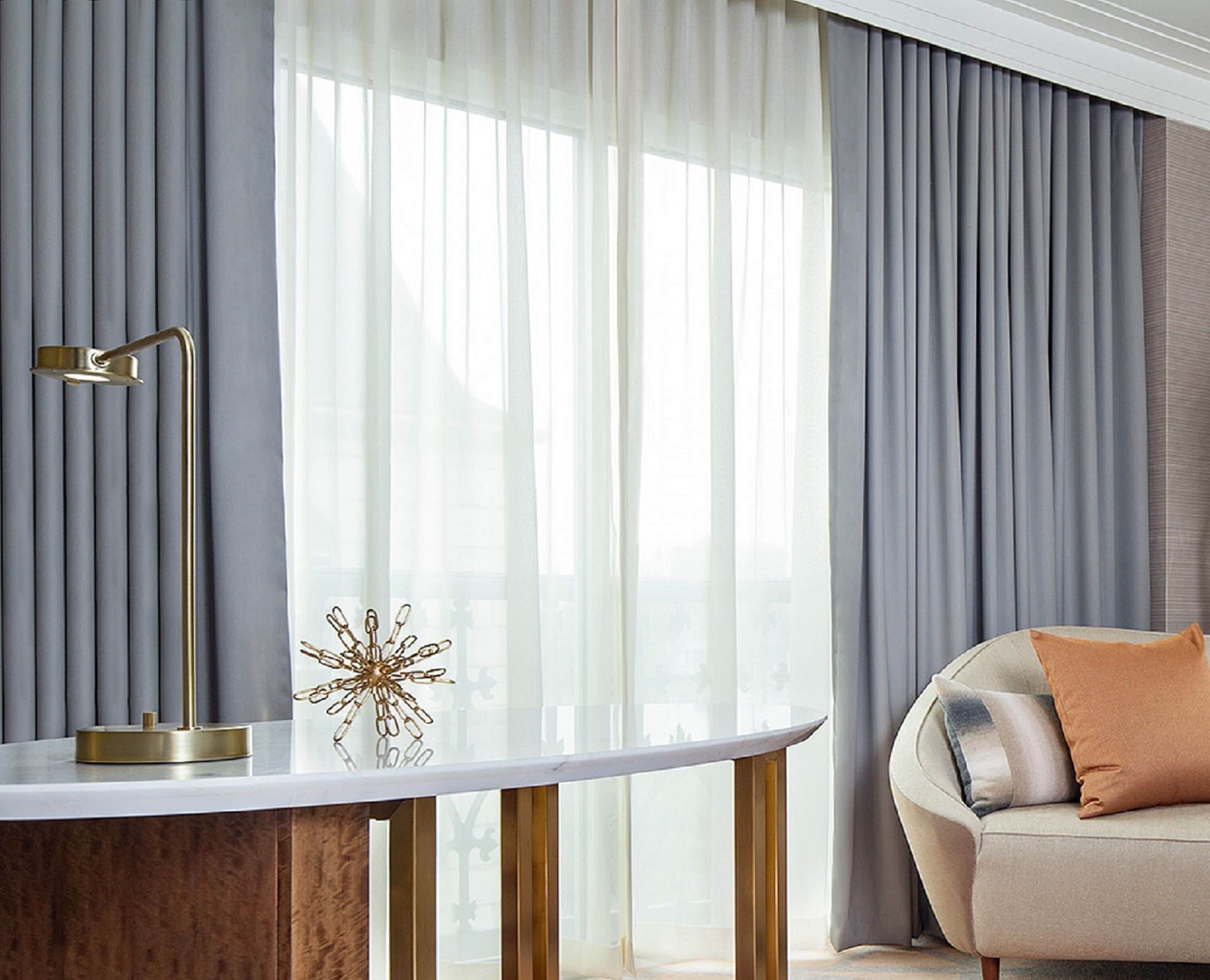 A modern living room with a round table, a gold floor lamp, and a decorative glass object.