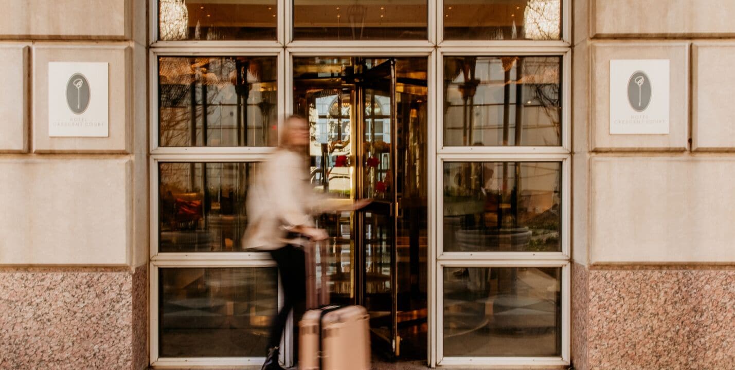 A hotel entrance with a revolving door, large windows, and framed signs on the walls.
