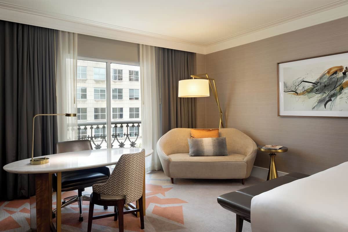 Ein Hotelzimmer mit Schreibtisch, Stuhl, Sofa und Nachttisch.