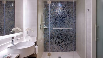 A modern bathroom with a glass-enclosed shower, a white sink, and a mirror.