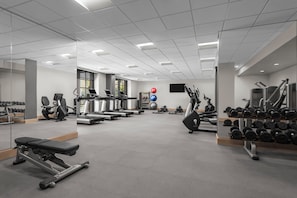 A gym with exercise equipment, mirrors, and a wall-mounted TV. - Hyatt Regency La Jolla (San Diego)