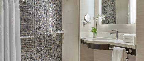 Une salle de bain moderne avec une douche, un lavabo et un miroir.
