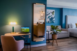 A modern hotel room with a desk, laptop, and a large mirror.