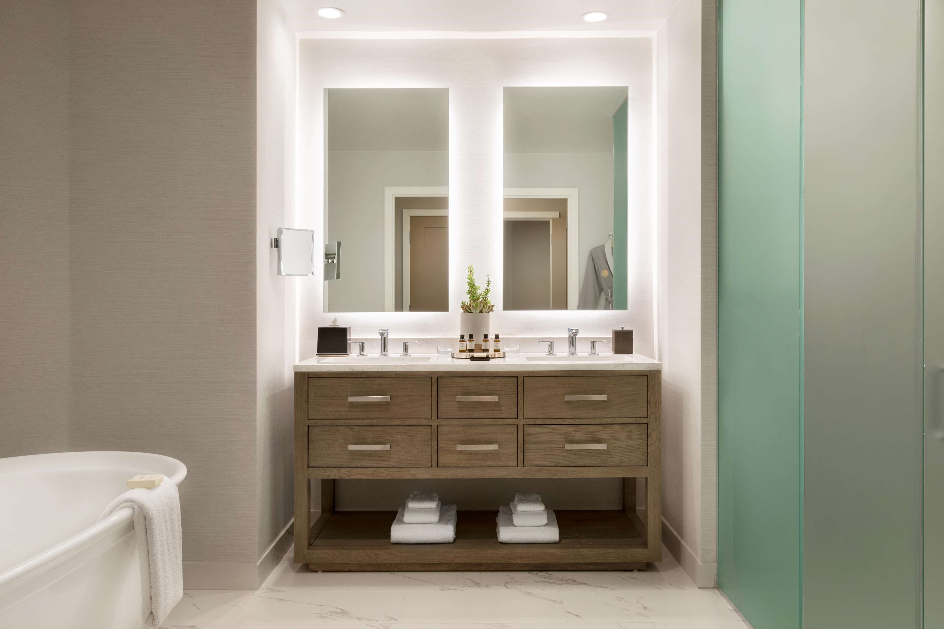 A modern bathroom with a double vanity, a large mirror, and a built-in shelf with towels.
