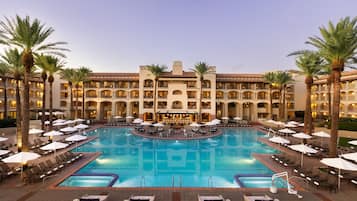 Un hôtel doté d’une grande piscine centrale, de nombreux balcons et de palmiers.