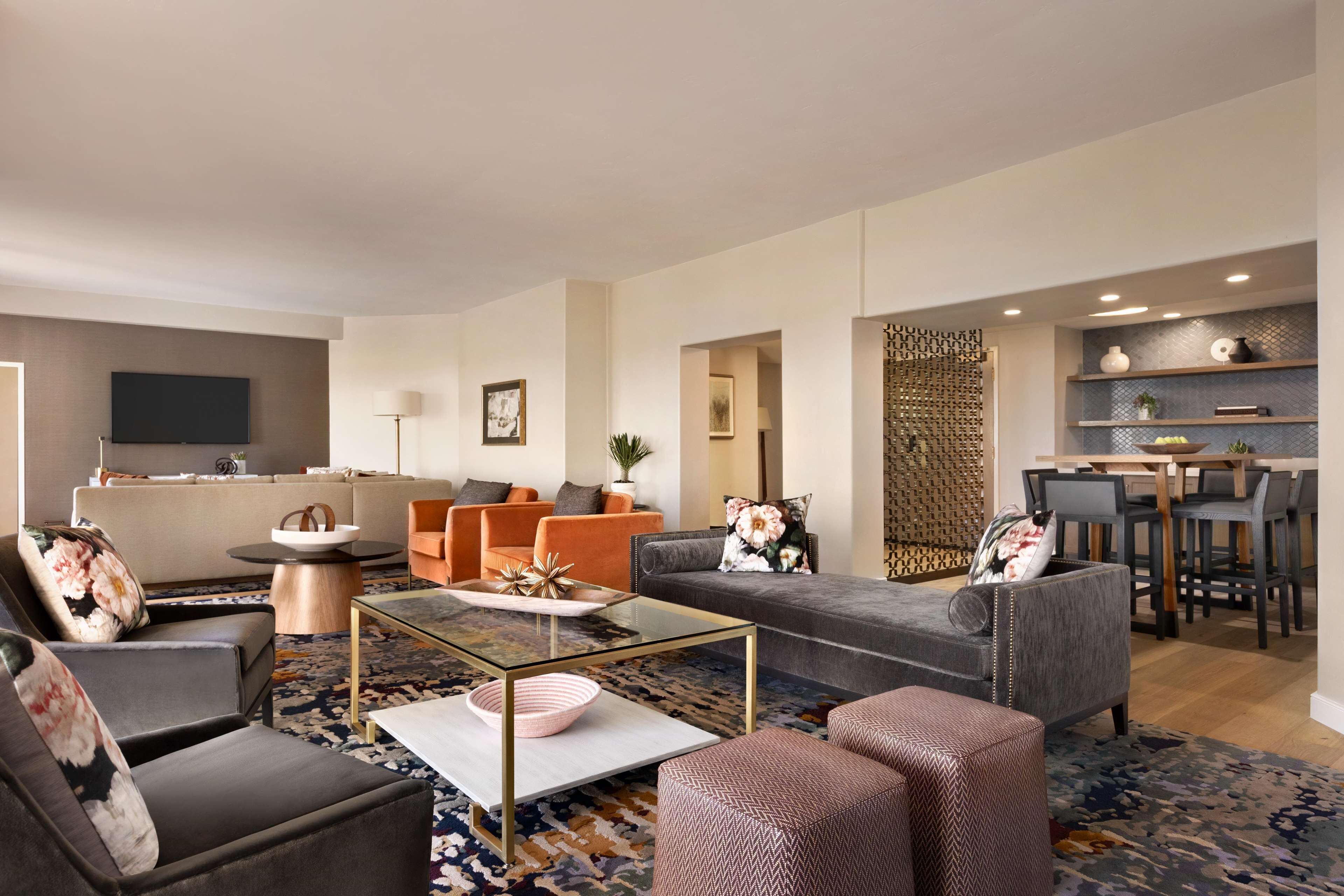 Uma sala de estar moderna com sofá, poltronas, mesa de centro e um espaço de jantar com cadeiras e mesa.