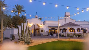A white building with arched windows and a tiled roof, surrounded by cacti and a well-maintained lawn. - Fairmont Scottsdale Princess (Scottsdale)