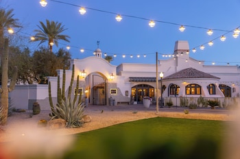 An outdoor seating area with fire pits and cushioned seating, overlooking a building with multiple balconies and a bar. at Fairmont Scottsdale Princess