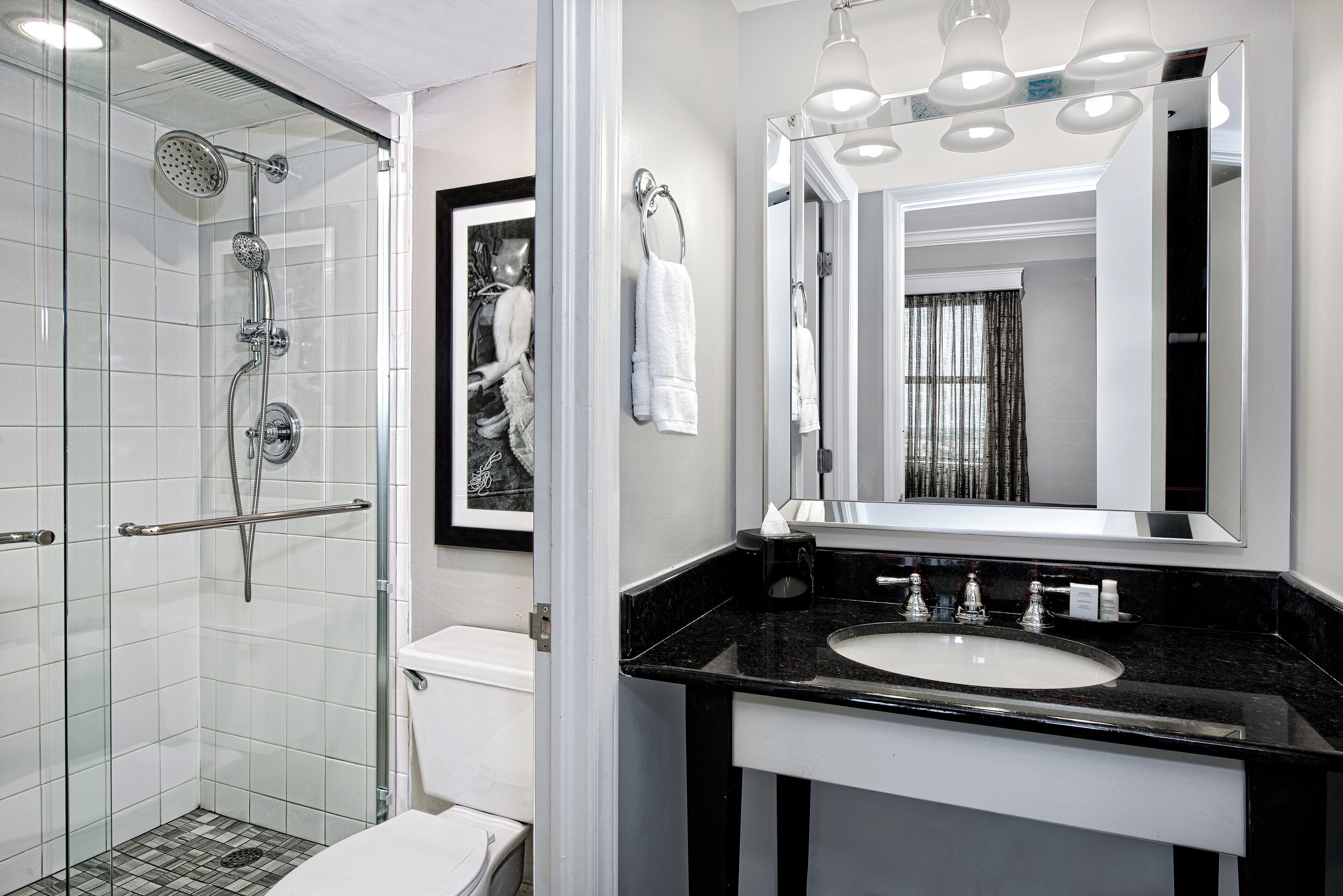 A modern bathroom with a glass-enclosed shower, a black countertop sink, and a large mirror.
