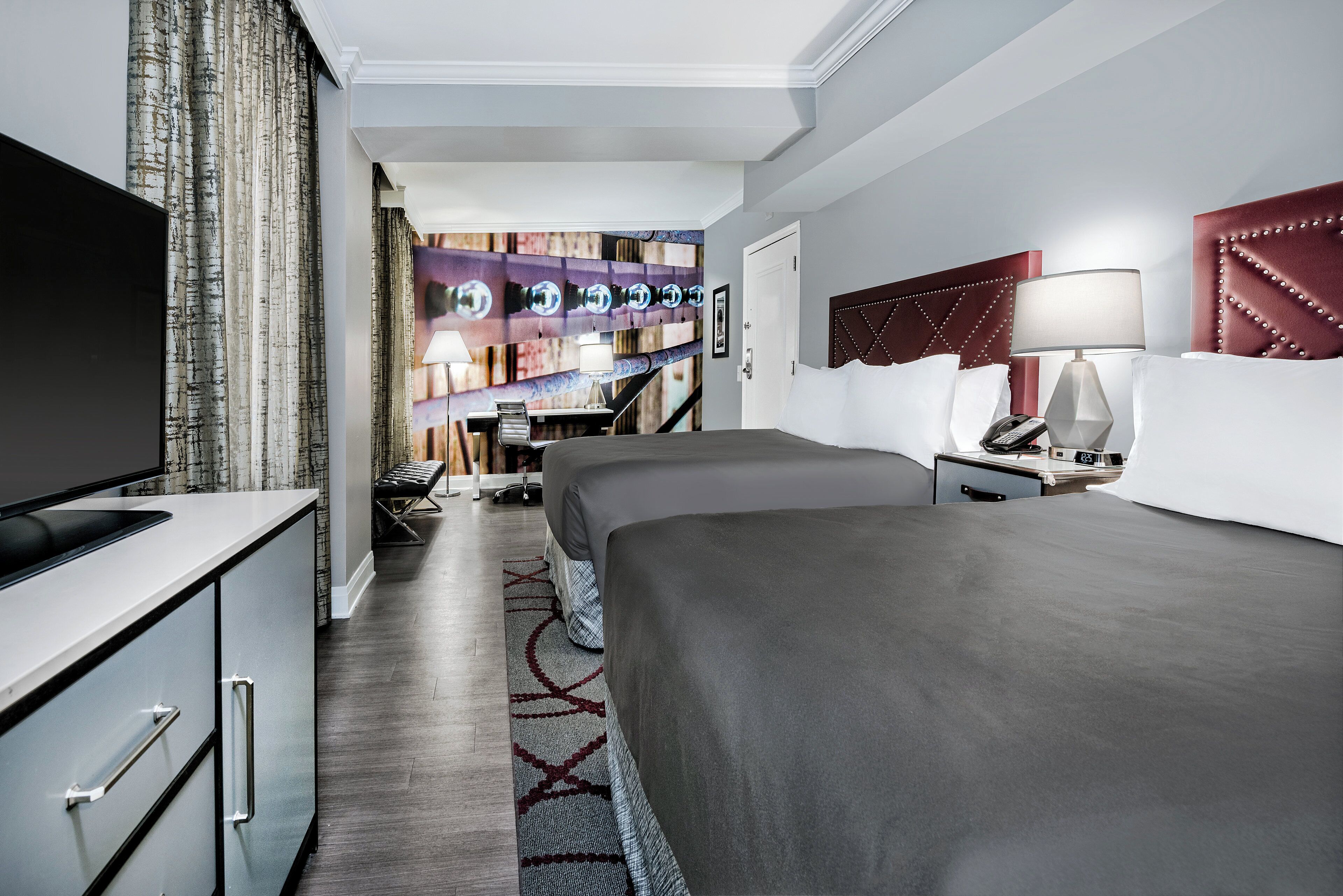 Una habitación de hotel con televisión, dos camas, escritorio y baño.