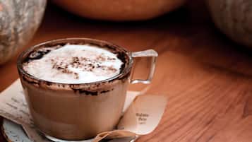 Una taza de chocolate caliente con crema batida y virutas de chocolate sobre una mesa de madera.