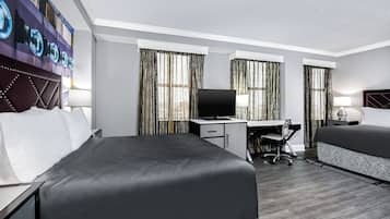 A hotel room with a bed, desk, chair, TV, and curtains.
