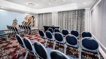 A conference room with rows of chairs, a large screen, and a patterned curtain backdrop.