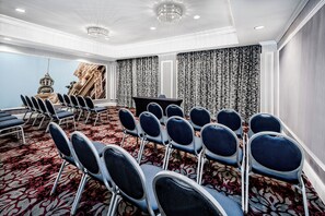 A conference room with rows of chairs, a large screen, and a patterned curtain backdrop. - Hotel Indigo Dallas Downtown by IHG (Dallas)