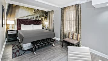 A hotel room with a large bed, a bedside table with a lamp, a chair, and a bench.