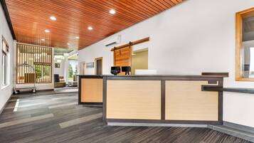A reception area with a wooden reception desk, a sliding door, and a view of the outdoors.