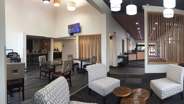 En modern hotellobby med en receptionsdisk, en sittgrupp och stora fönster med utsikt över omgivningarna.