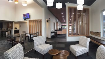 Relax in our stylish lobby, featuring a reception area, comfortable seating, and a dining space with a glass-top table.