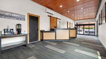 A reception area with a wooden ceiling, a coffee machine, and a cityscape painting.