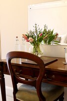 Una mesa de madera para comer con un florero y dos botellas vacías.
