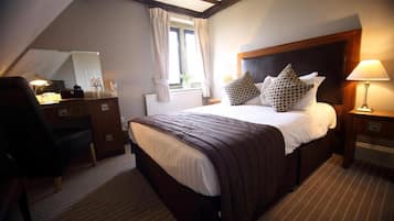 Une chambre d’hôtel avec un grand lit, un bureau, une chaise, une lampe et une fenêtre avec des rideaux.