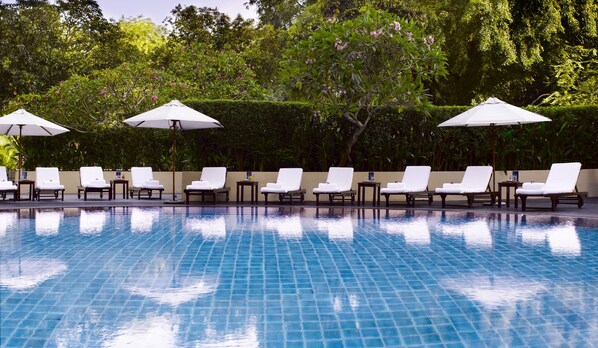 Una piscina al aire libre, sombrillas, tumbonas