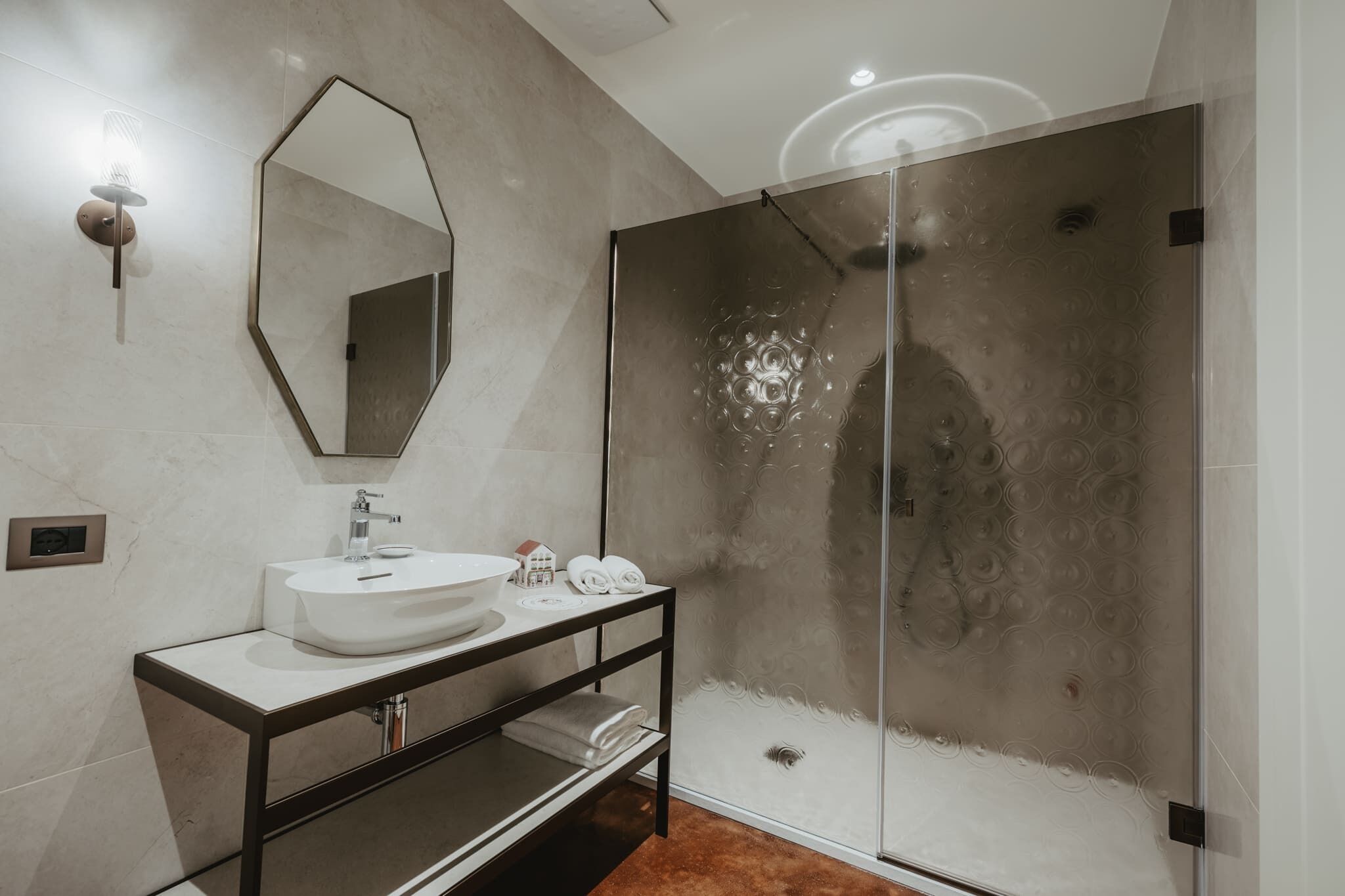Un bany modern amb un mirall gran, un lavabo blanc i una dutxa amb portes de vidre.