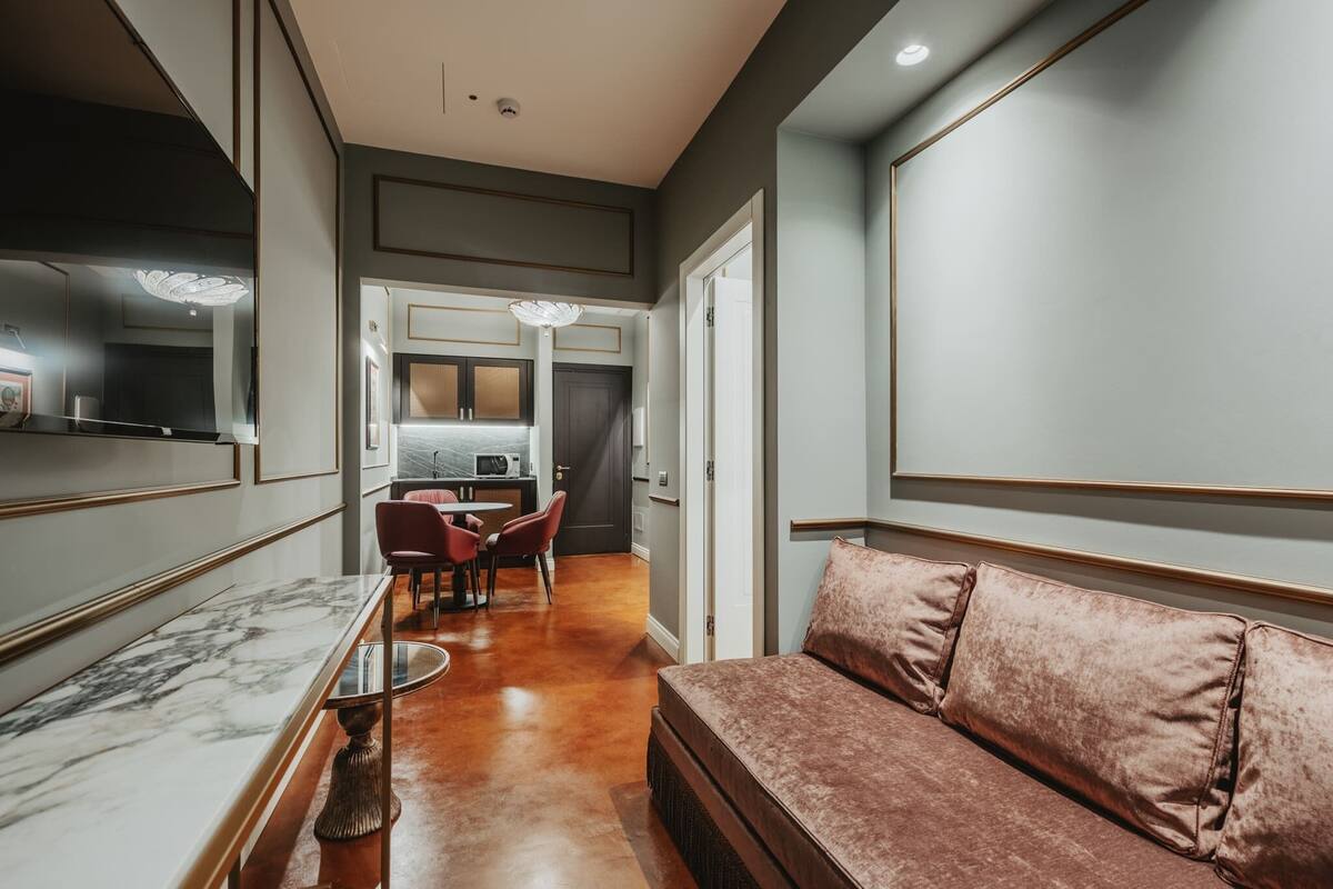 A modern interior with a marble dining table, a plush sofa, and a kitchen area in the background.