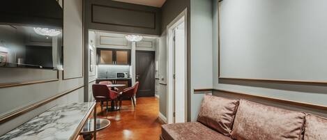 A modern interior with a marble dining table, a plush sofa, and a kitchen area in the background.