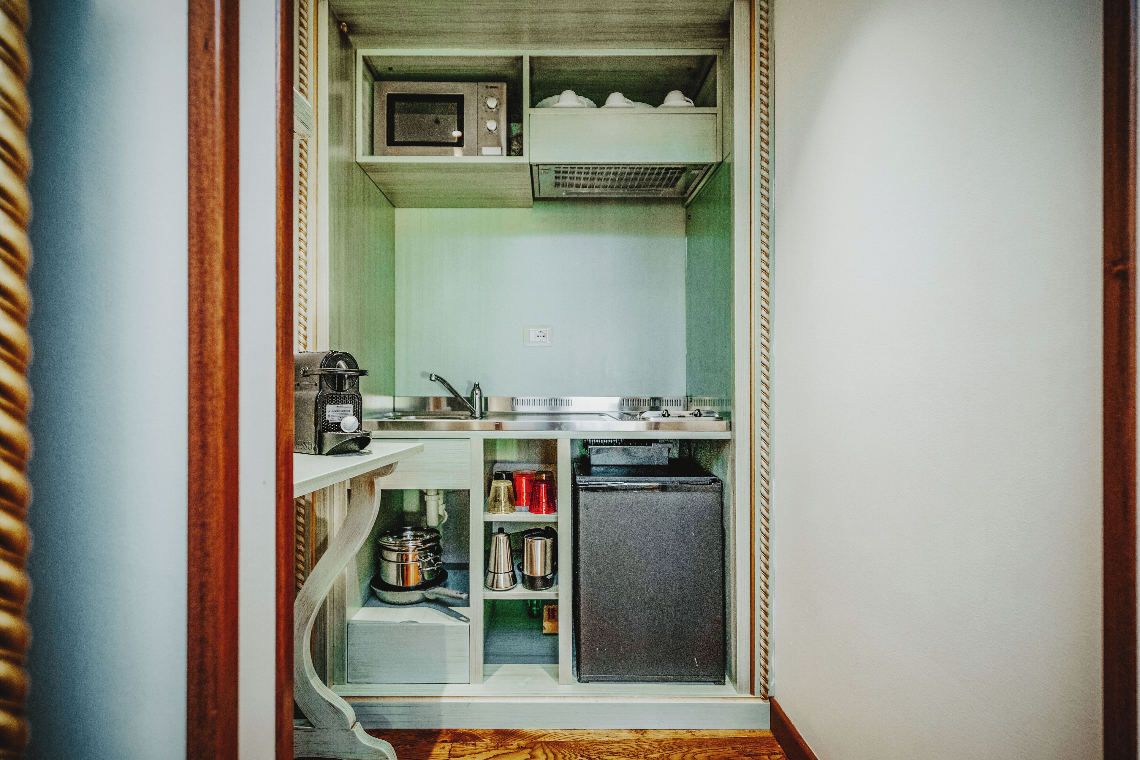 Una cocina compacta con microondas, cafetera y un refrigerador pequeño.
