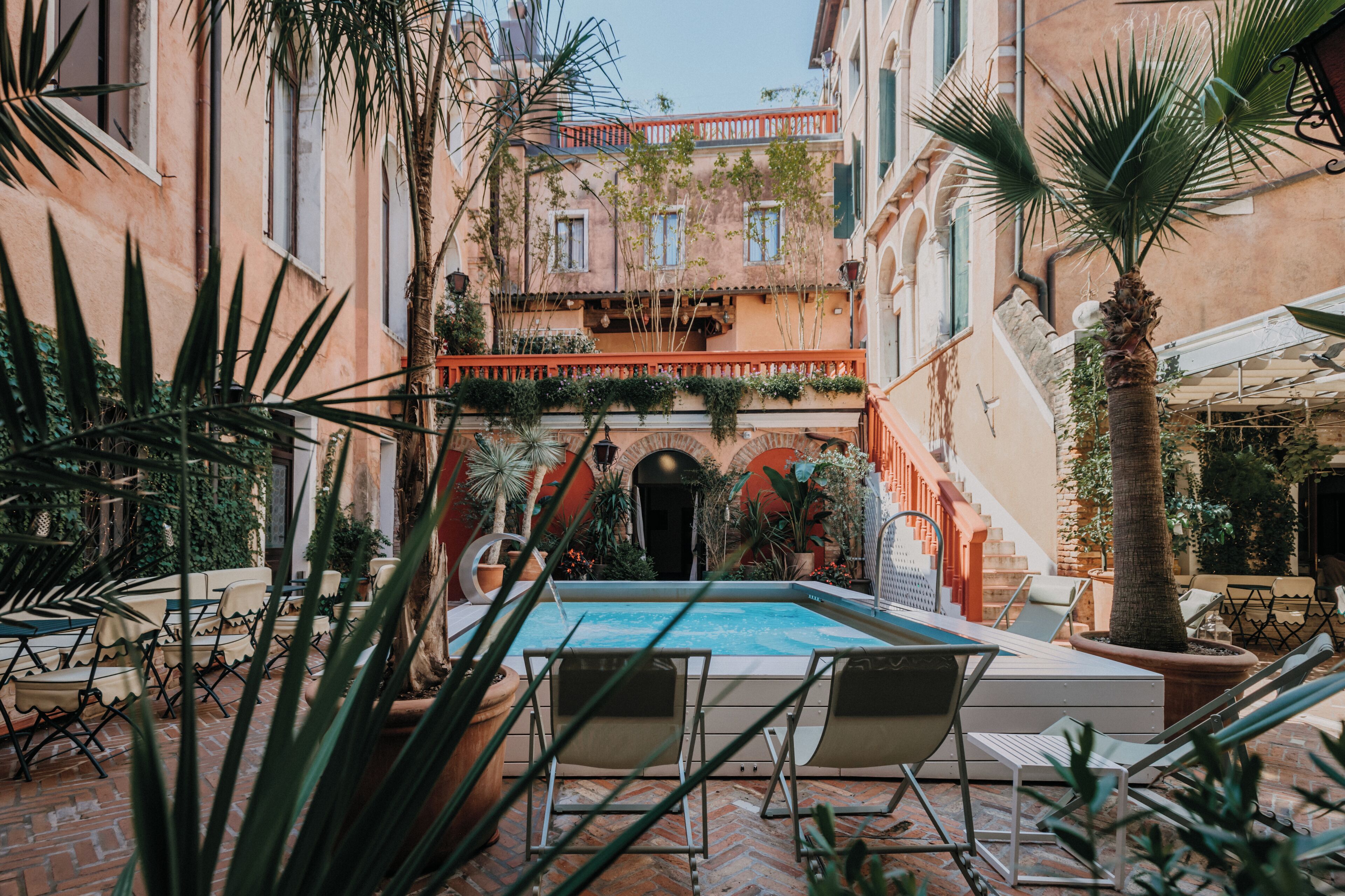 Une cour avec une piscine, des chaises longues et des plantes en pot.