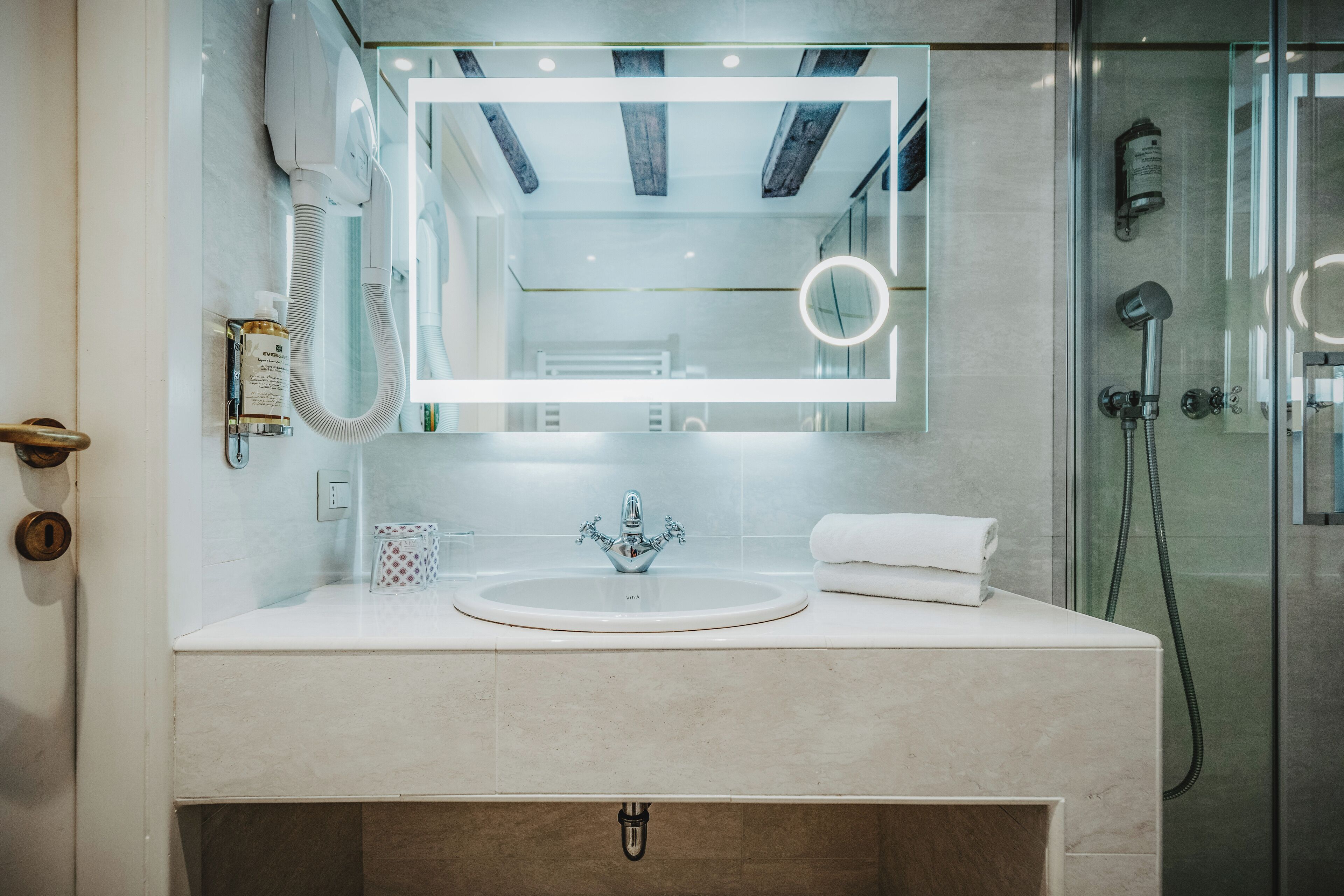 Un bagno moderno con uno specchio grande, un lavandino e una doccia.