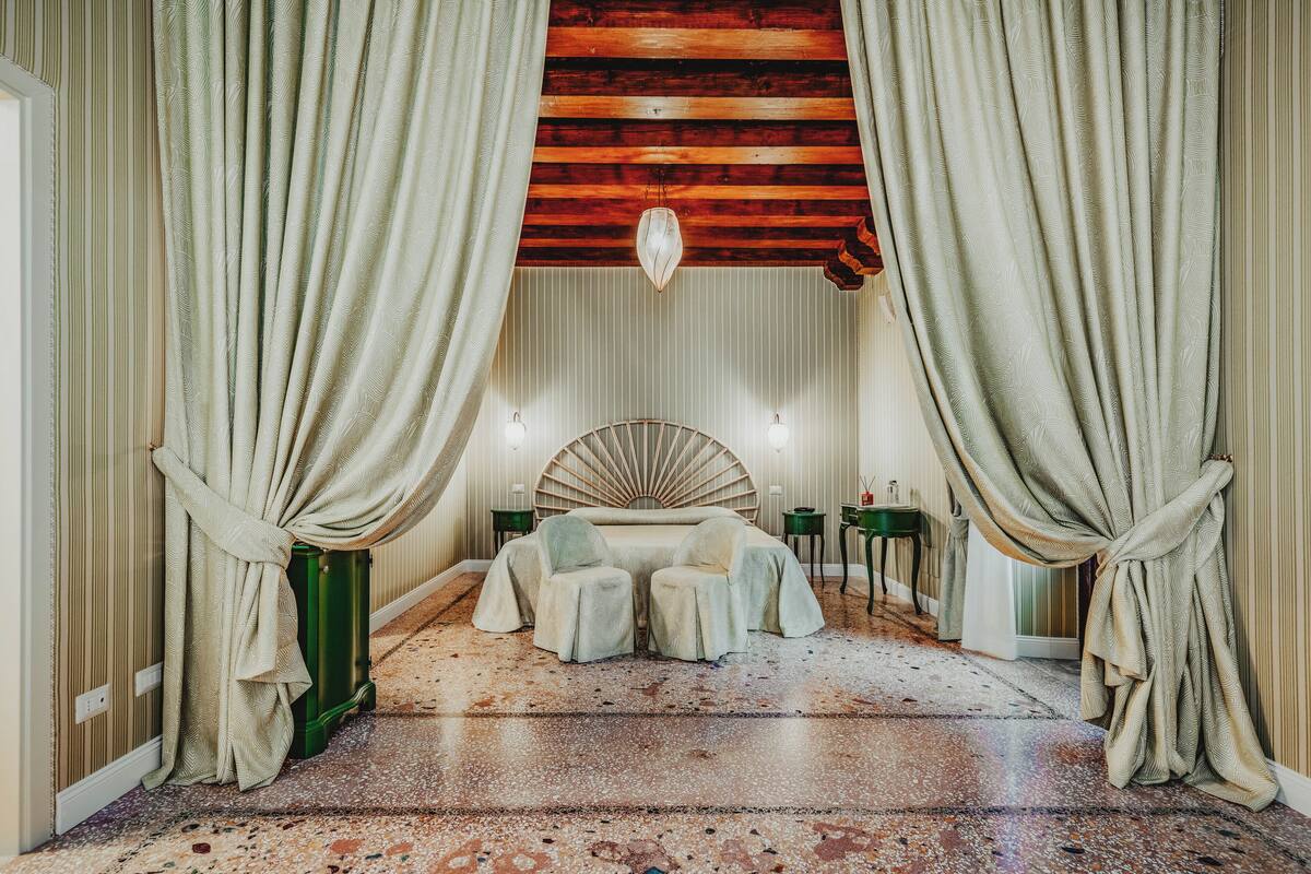 A room with a bed, two chairs, a round table, and a decorative ceiling.