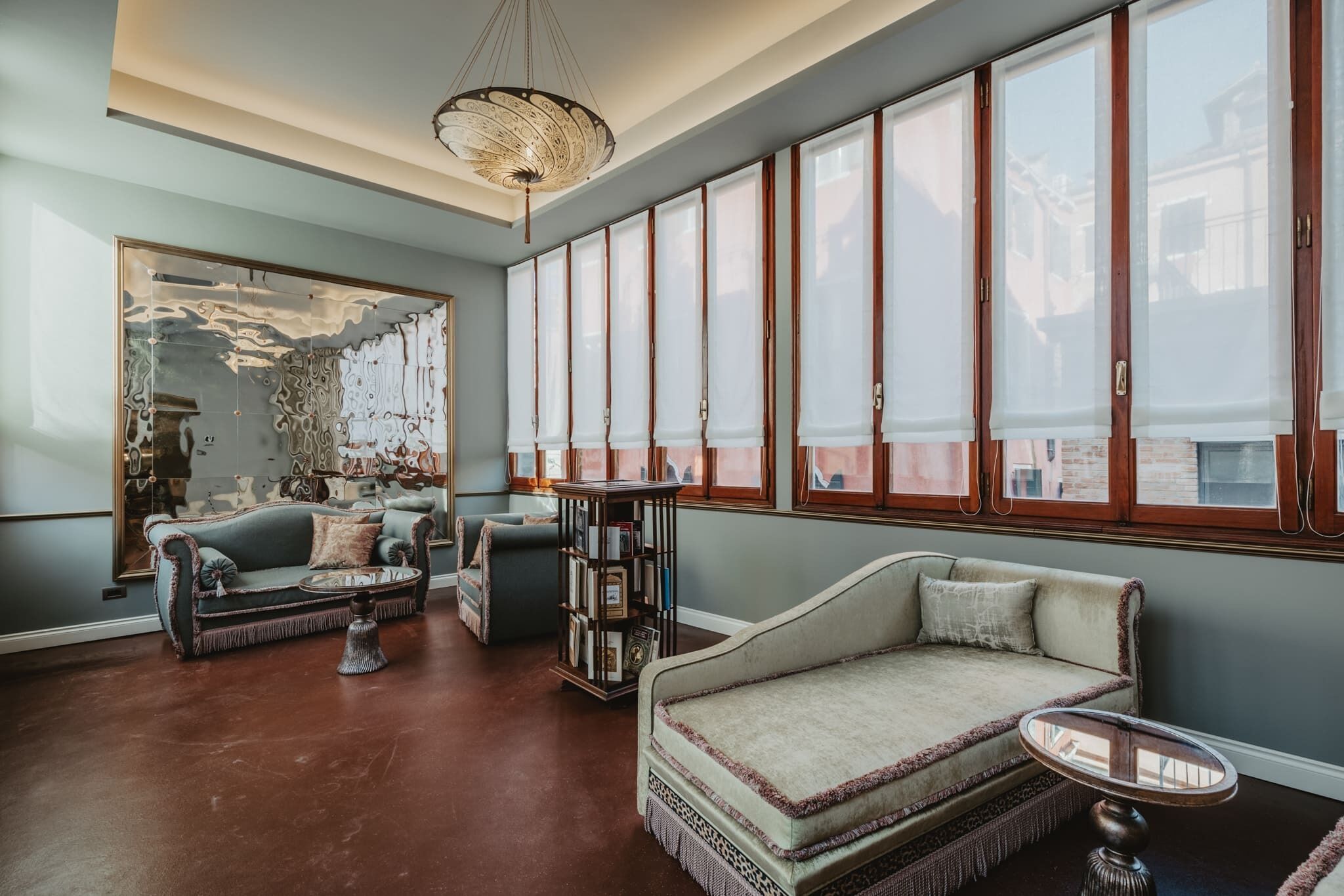 A spacious living room with a large mirror, two sofas, a coffee table, and a bookshelf.