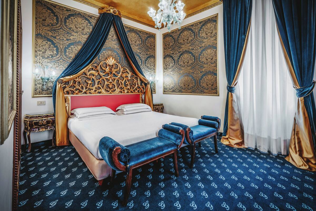 A luxurious bedroom with a canopy bed, a red headboard, and a patterned carpet.