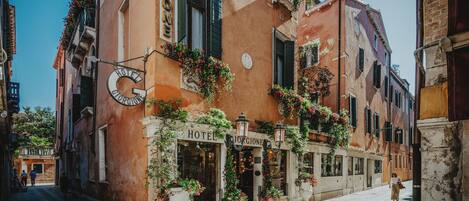 A hotel with a classic facade, large windows, and outdoor flower arrangements.