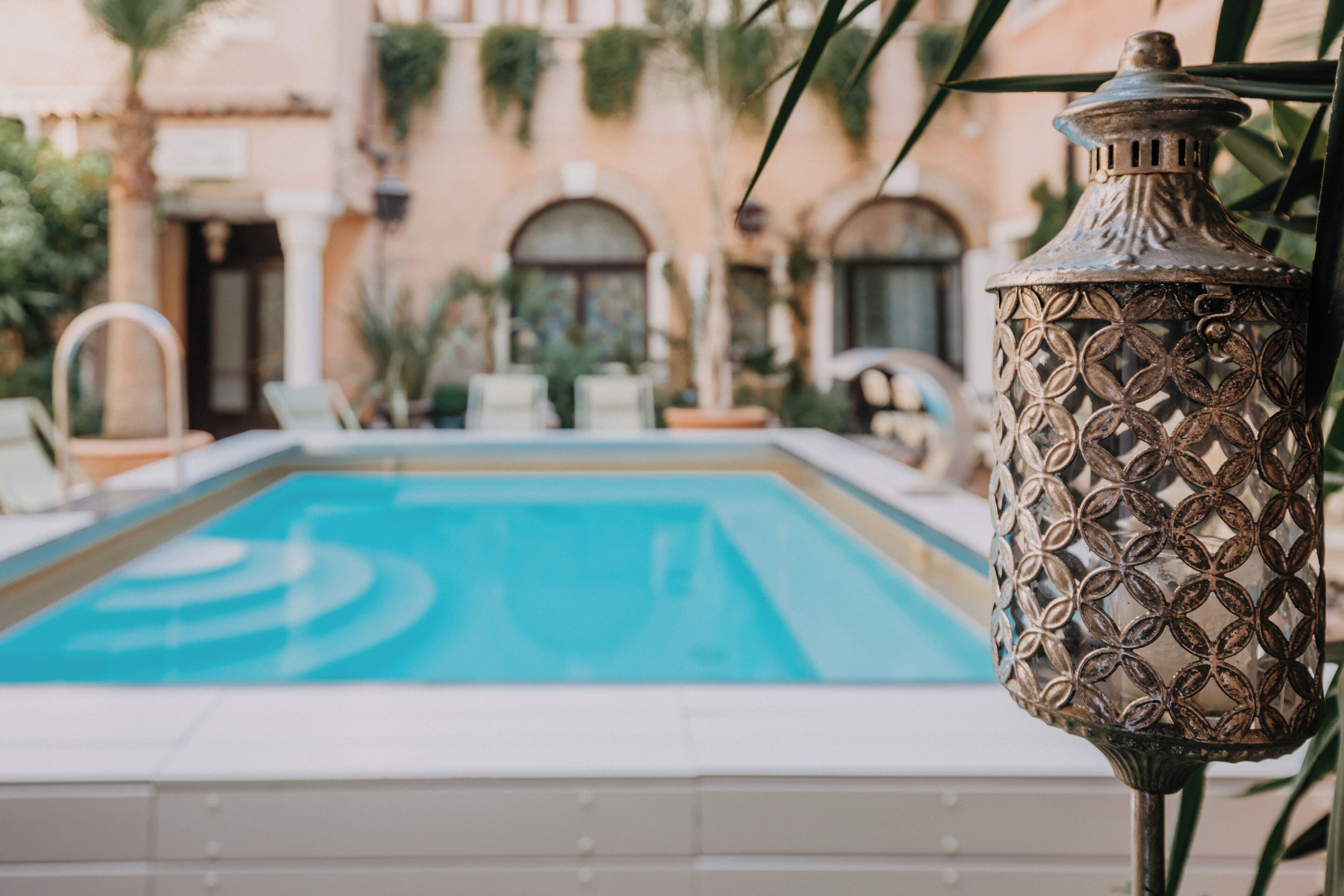 A pool with a decorative metal lamp in the foreground.