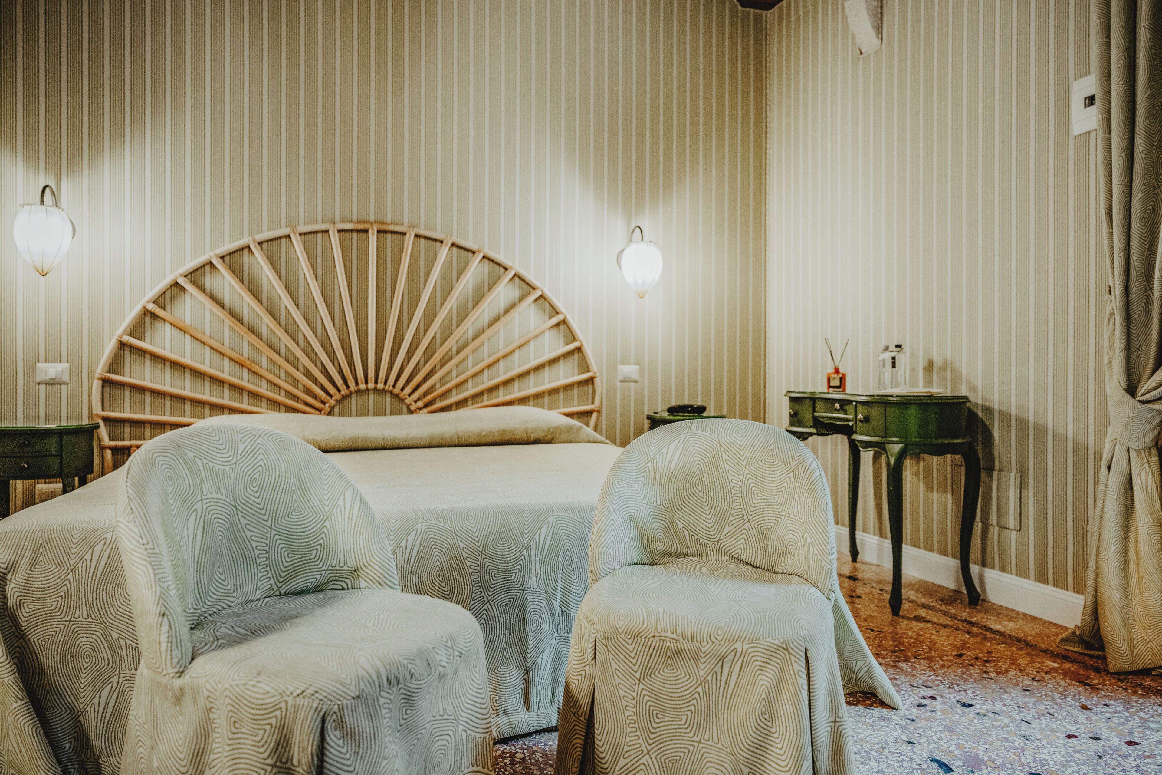 Ein Hotelzimmer mit einem großen Bett, zwei Sesseln, einem kleinen Tisch und einer Wandleuchte.