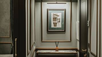 A narrow hallway with a framed picture on the wall, a small table with a vase, and a door on the right.