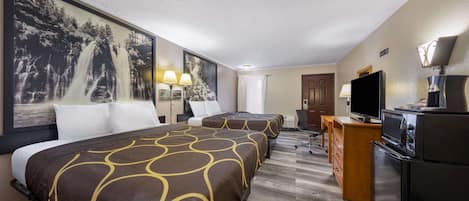 A hotel room with two beds, a TV, a refrigerator, and a desk with a lamp.
