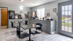 A modern kitchen with grey cabinets, a black countertop, and a tiled backsplash.