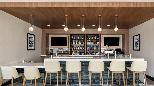 A bar area with a long counter, multiple stools, and a well-stocked bar. - Holiday Inn Ontario by IHG (Ontario)