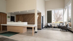 A modern office space with a reception desk, seating area, and large windows offering views of the outdoors. - Holiday Inn Ontario by IHG (Ontario)