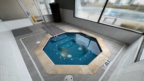 An indoor octagonal hot tub with a tiled floor and a metal ladder. - Holiday Inn Ontario by IHG (Ontario)