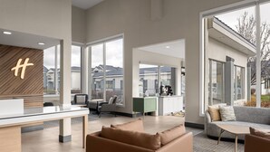A modern hotel lobby with a reception desk, seating area, and large windows offering views of the outside. - Holiday Inn Ontario by IHG (Ontario)