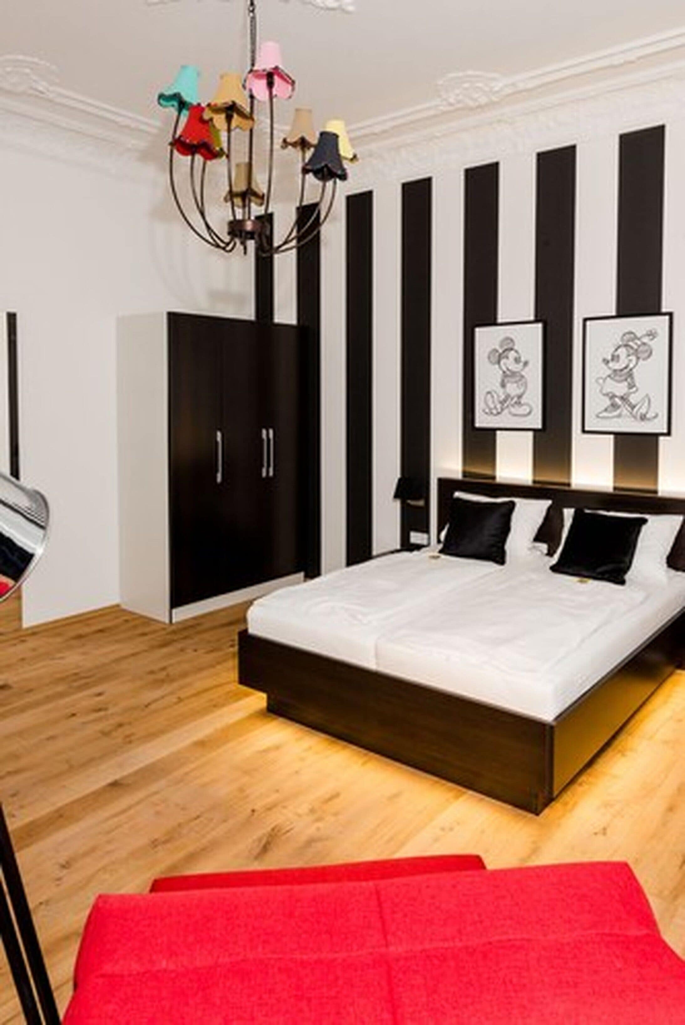 A bedroom with a bed, a wardrobe, and a chandelier.