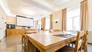 A spacious conference room with a large wooden table, multiple chairs, a projector screen, and a television. - The Heidelberg Exzellenz Hotel (Heidelberg)