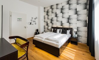 Una habitación de hotel con una cama, un escritorio, una silla y un papel tapiz estampado.