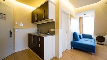 A compact living space with a kitchenette, a sofa, and a window with curtains.
